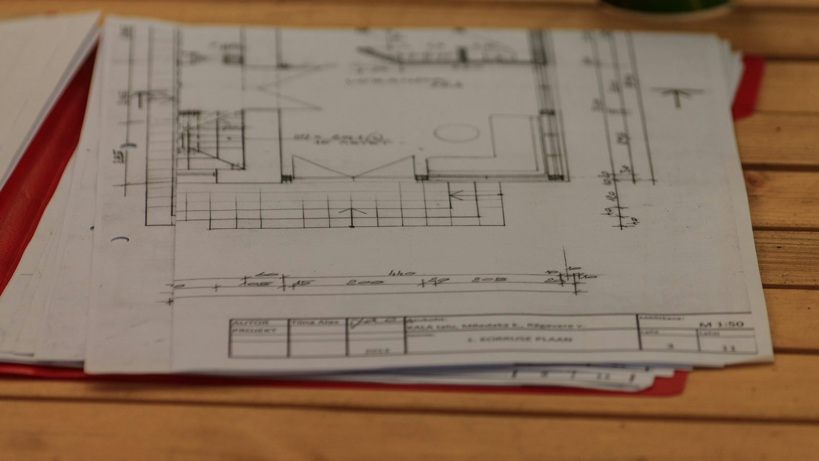 Plans d'une salle de bain posés sur une table en bois, cotes et annotations