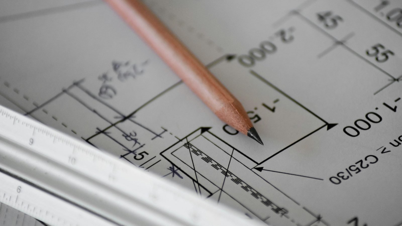 Crayon et règle posés sur un plan d'architecte coté