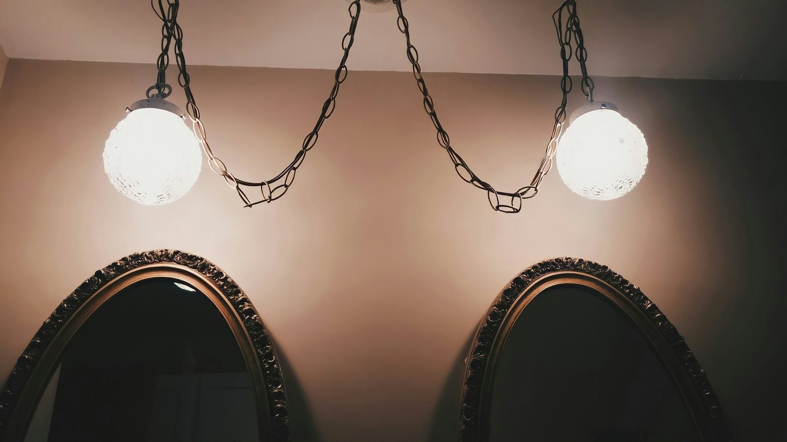 Deux miroirs anciens éclairés chacun par une suspension, lumière chaude