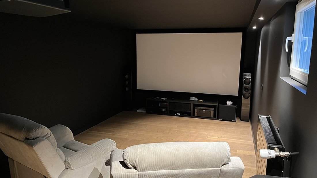 Salle de cinéma privée aménagée : grand écran, fauteuils en velours côtelé, parquet clair et murs sombres