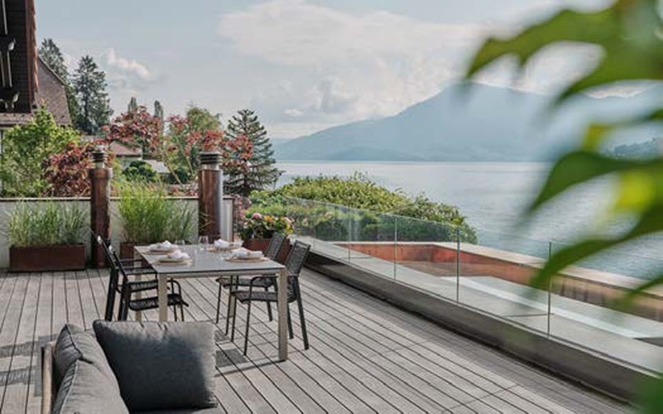 Terrasse en Accoya gris avec salon de jardin, vue sur un lac et les montagnes