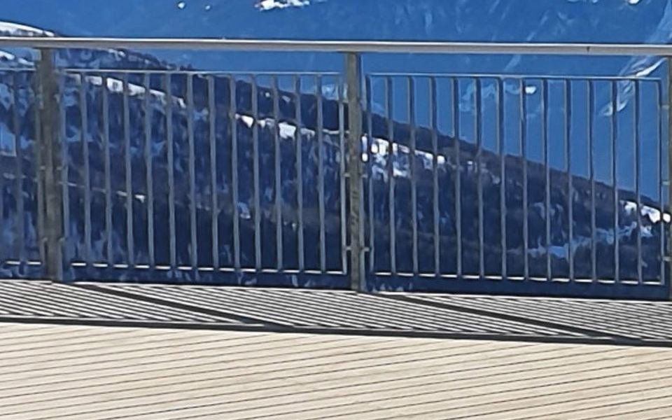 Balcon en lames Accoya claires face aux montagnes enneigées