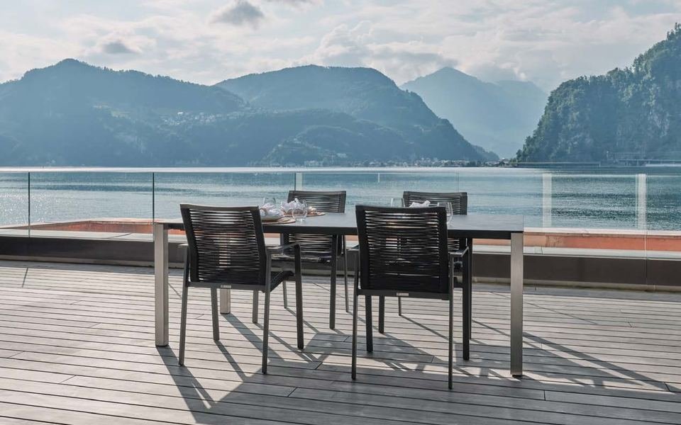 Terrasse en lames de bois gris avec table et chaises face au lac et aux montagnes