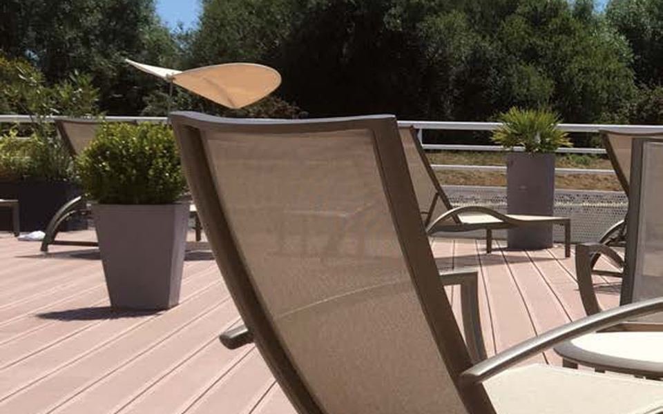 Terrasse en lames composite brun-rouge avec deux chaises longues au soleil