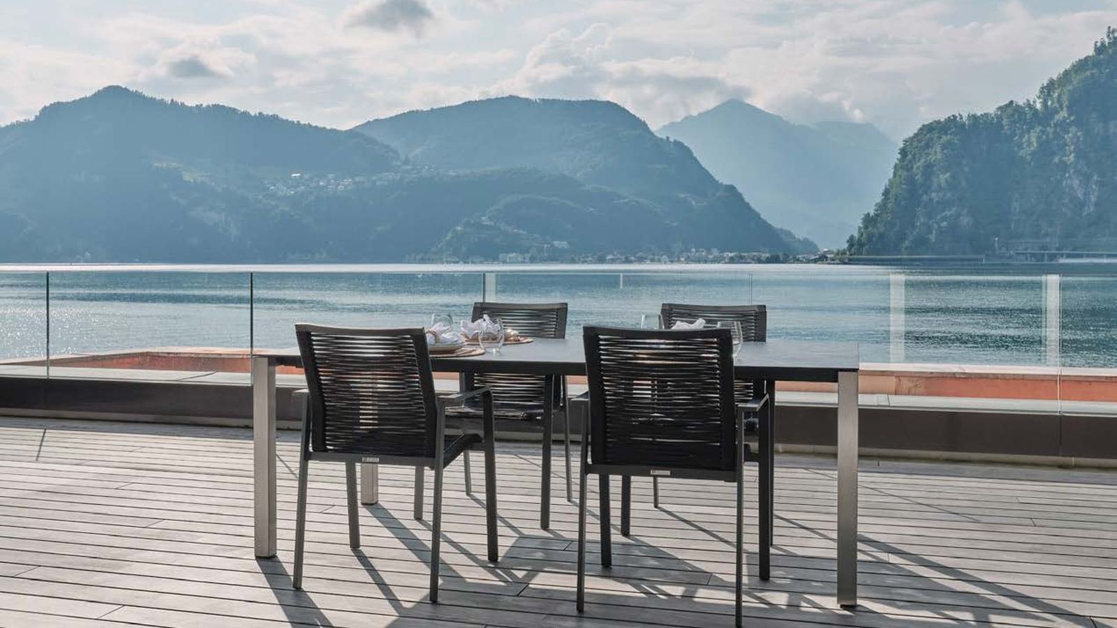 Terrasse en lames de bois gris, table dressée, vue sur le lac Léman et les montagnes