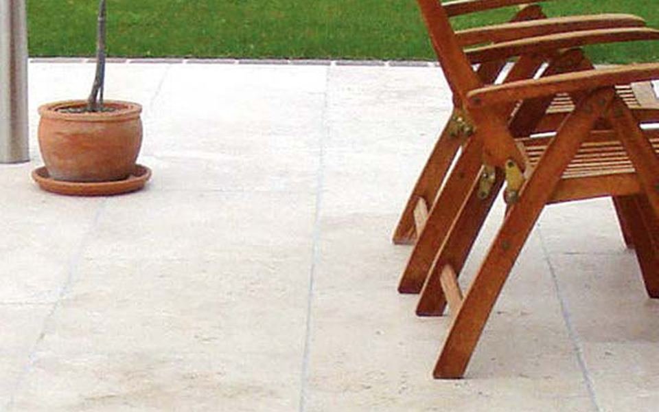 Terrasse en dalles de travertin beige avec fauteuils en bois