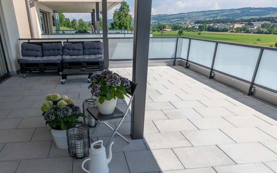 Terrasse en dalles béton grand format, fleurs et campagne en arrière-plan